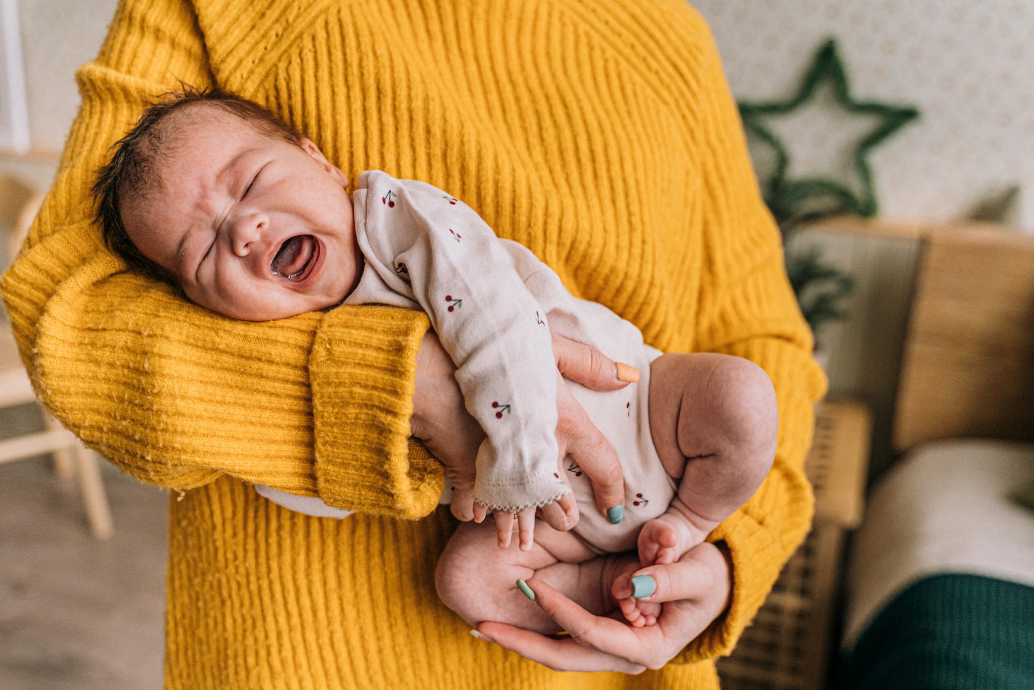 bébé qui pleure dans les bras d'une femme